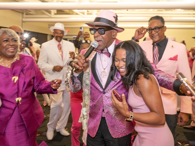 Fast Freddy Anderson on the microphone sharing a laugh with guests on the dance floor. 80th birthday celebration.