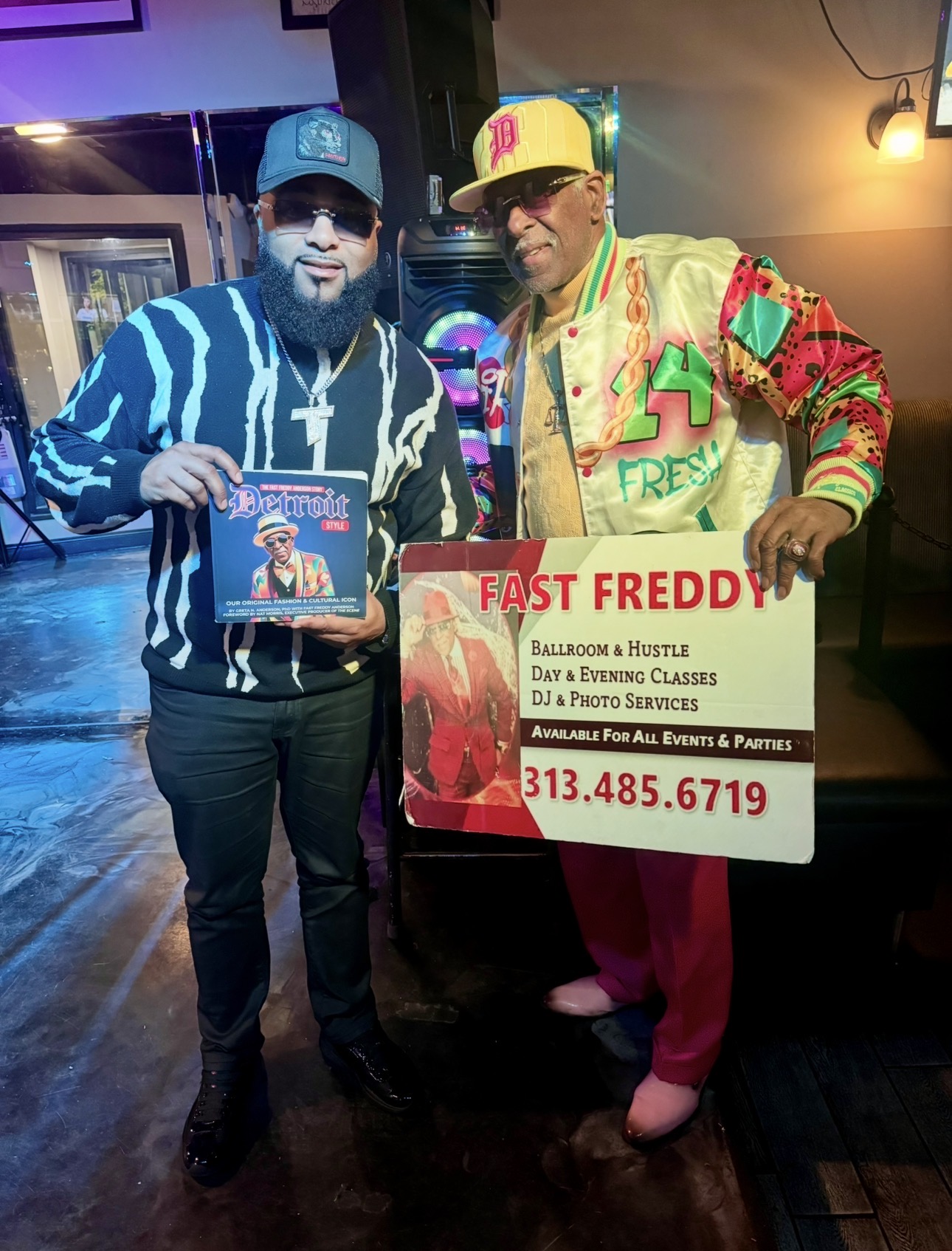 Fast Freddy Anderson with a supporter proudly holding the Detroit Style book and a Fast Freddy promotional sign.