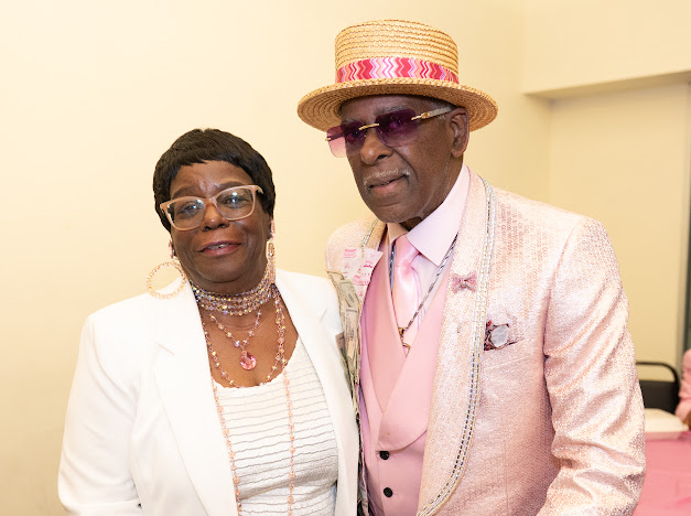 Fast Freddy Anderson posing with a guest in a white jacket and pearls. 80th birthday celebration.