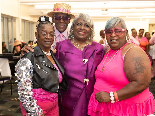 Fast Freddy Anderson surrounded by guests in pink, purple and sequins. 80th birthday celebration.