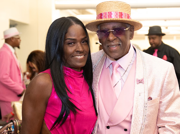 Fast Freddy Anderson smiling with a guest in a hot pink top. 80th birthday celebration.
