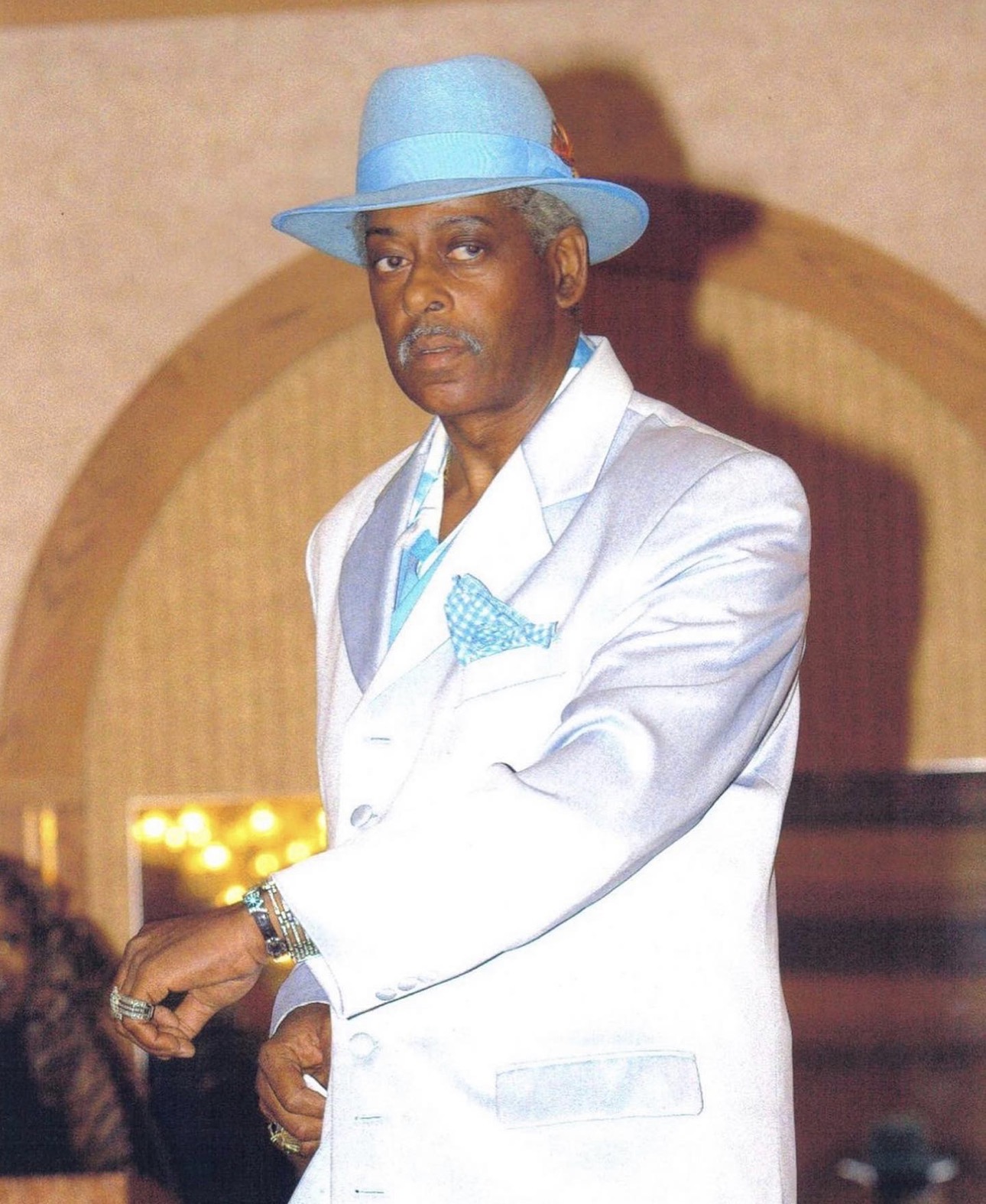 Fast Freddy walking a runway in a white suit and powder blue hat