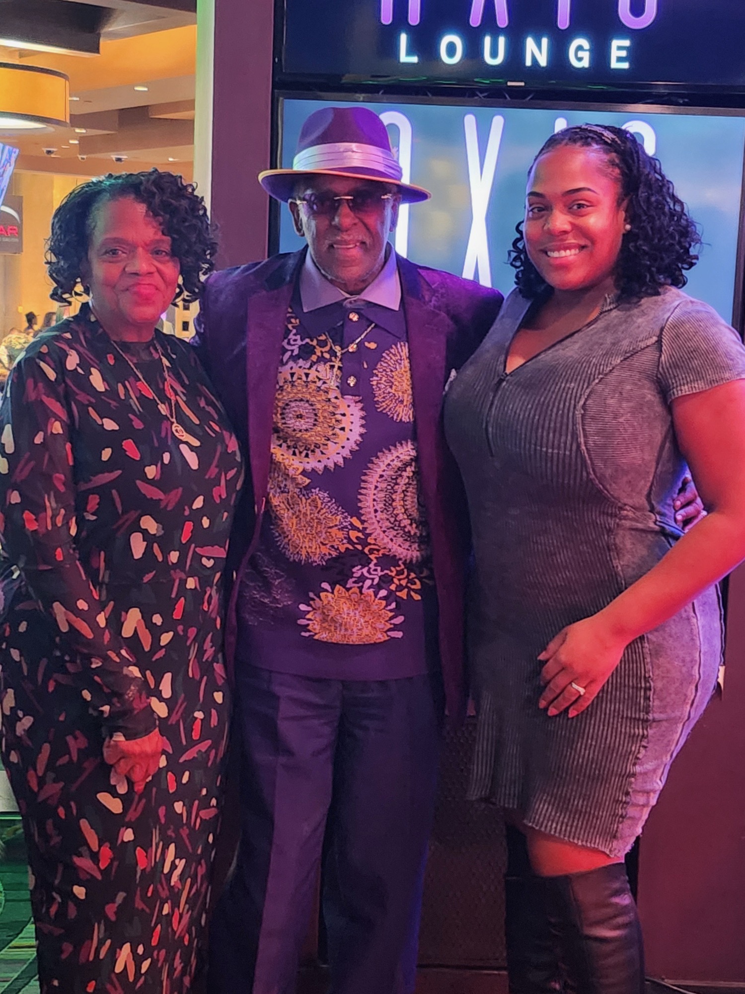 Fast Freddy Anderson in a purple suit and fedora with two supporters at the Axis Lounge.