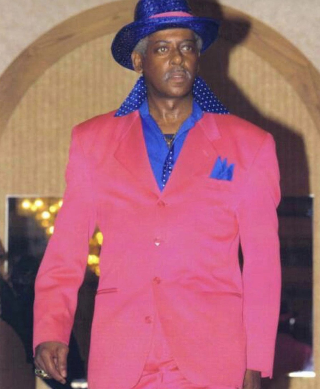 Fast Freddy Anderson on the runway in a coral pink suit with a blue polka dot hat.